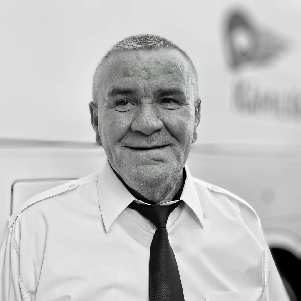 Black and white portrait of a smiling elderly man in formal attire, exuding warmth.