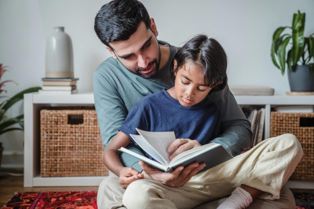 A father reading a book with his son, enjoying quality time together indoors.